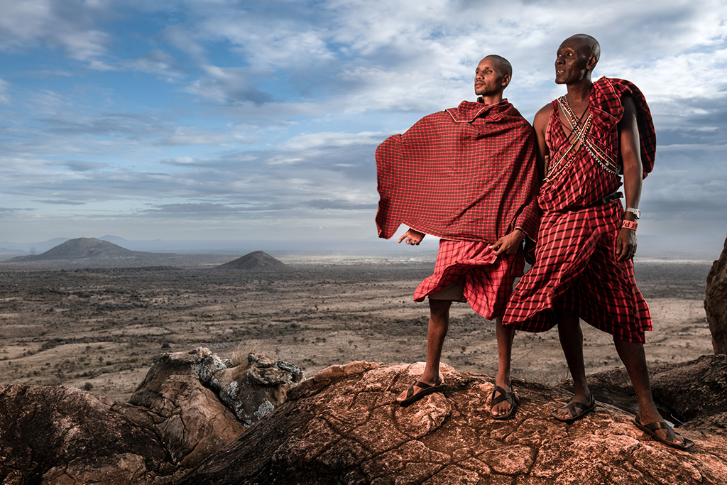 colour photo of two mean standing on rock