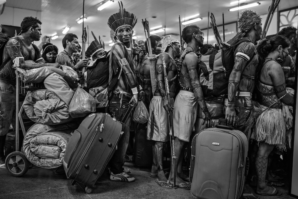 Members of the Munduruku community line up to board a plane at Altamira Airport, in Pará, Brazil, on 14 June 2013. After protesting at the site of the construction of the Belo Monte Dam on the Xingu River, they traveled to the national capital Brasilia to present their demands to the government. The Munduruku community inhabit the banks of another tributary of the Amazon, the Tapajos River, several hundred kilometres away, where the government has plans to build further hydroelectric projects. Despite pressure from indigenous people, environmentalists and non-governmental organisations, the Belo Monte project was built and completed in 2019
