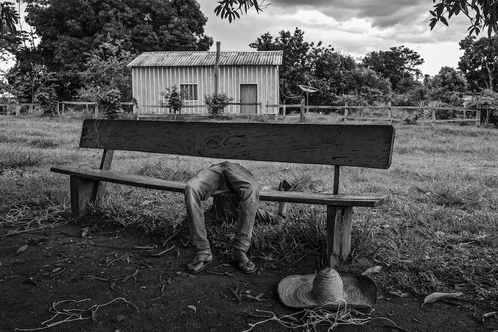 A member of the Quilombola community – an Afro-Brazilian community consisting of Black Brazilians, some of whom are descendants of enslaved peoples from the African continent – lies passed out drunk on a bench, in Pedras Negras, São Francisco do Guaporé, Rondônia, Brazil, on 29 January 2021. The process of providing land deeds to communities started by former enslaved people was already slow before Jair Bolsonaro's election. It has now stalled completely, as a result of the president’s resolve not to demarcate further land for such communities in the Amazon