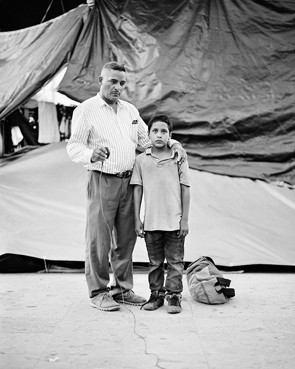Edwardo Benavides, age 40 and his son Jonathon Benavides Reyes, age 9, are migrants from La Union, El Salvador. They took a portrait at an informal migrant camp at a municipal park in Reynosa, Tamaulipas, Mexico on 5 May 2021. Series Name: Migrantes. © Adam Ferguson, Australia, Photographer of the Year, Professional, Portraiture, 2022 Sony World Photography Awards