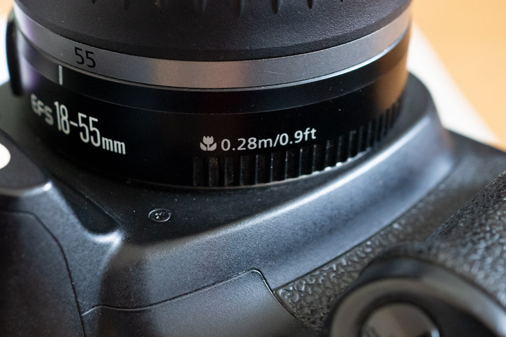 Canon EF 18-55mm lens shows the close-focus distance on the side