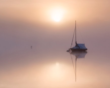 Boat on dead still water with misty weather