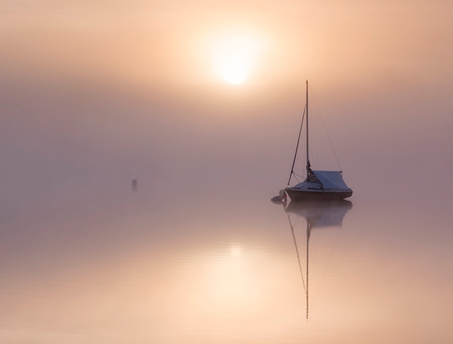 Boat on dead still water with misty weather