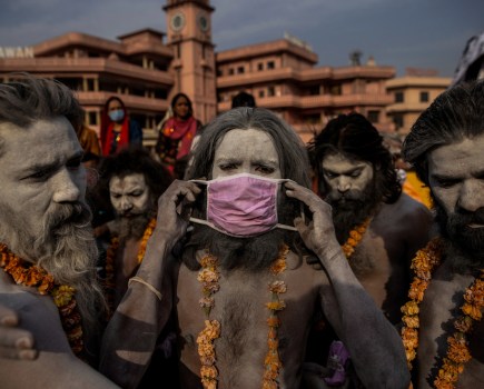 A ‘Naga Sadhu,’ or Hindu holy man, places a mask across his face before entering the Ganges river during the traditional Shahi Snan, or royal dip, at the Kumbh Mela festival in Haridwar, India, 12 April 2021. As COVID-19 cases and deaths exploded in India in April and May, hospitals ran so short of oxygen that many patients suffocated. © Danish Siddiqui/Reuters