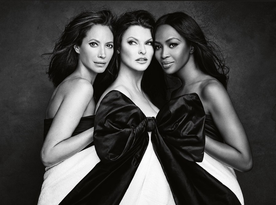 Black and white shot of three female models stood behind a large silk bow