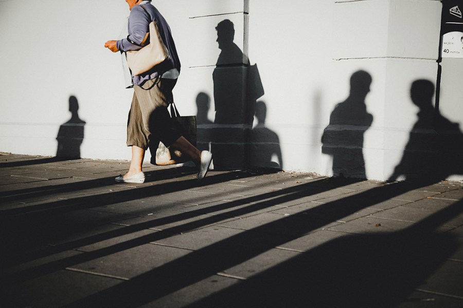 woman walking on path surrounded by silhouettes of other people street photography