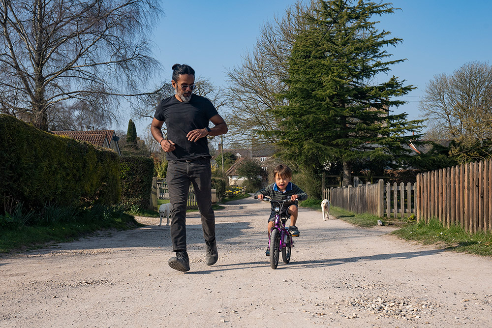 man running with child on bike 