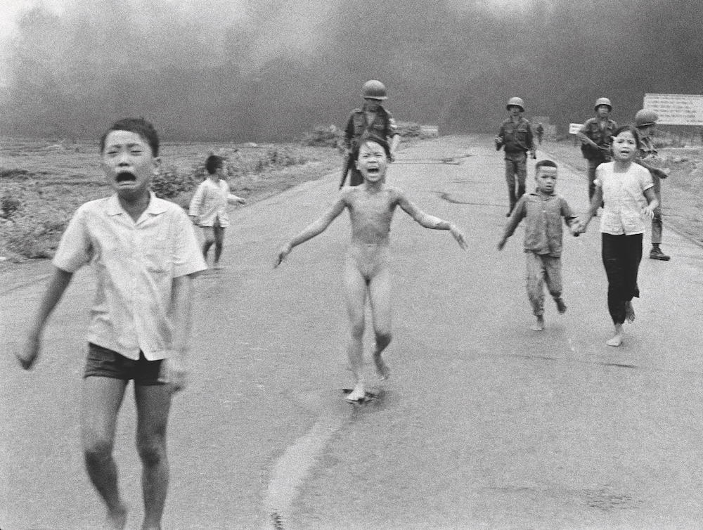 South Vietnamese forces follow behind terrified children, including 9-year-old Kim Phuc, centre, as they run down Route 1 near Trang Bang after an aerial napalm attack on suspected Viet Cong hiding places. The Terror of War, aka Napalm Girl. © Nick Ut/AP/Shutterstock 