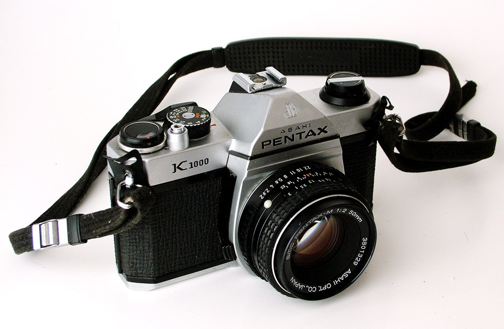 Pentax K1000 with lens and strap, © Michele M. F., Wikimedia Commons