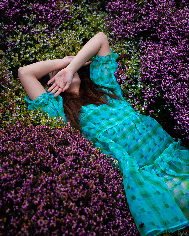 woman in green dress lying in purple heather
