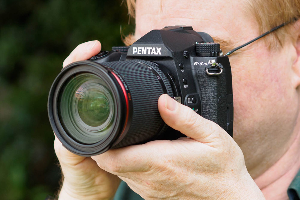 Pentax K-3 III, DSLR in hand with lens (Image: Andy Westlake)
