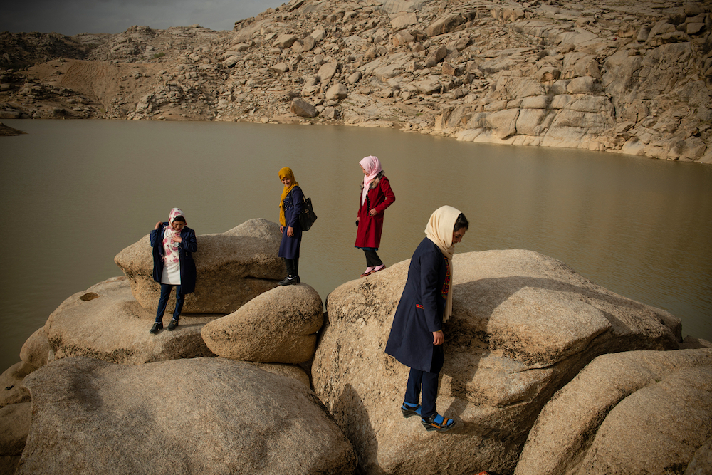 Nili, Daikundi, Afghanistan, 19 March 2021. One Friday afternoon, Nazanin (21, creme scarf) and her friends, Salima (22, floral scarf), Madina (19, yellow scarf) and Zulaikha (20, pink scarf), go out to Bandi Bargh (Electricity Dam) for a picnic, a day before the arrival of the new year. All girls are from far out districts of Daikundi and unable to go home for this year's Now Rooz celebration. This Now Rooz marks the start of a new century in Gregorian calendar. © Kiana Hayeri/LOBA 2022
