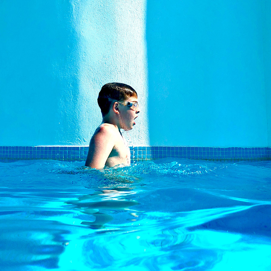 A boy with googles in blue swimming pool