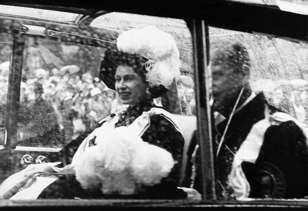 Queen Elizabeth II and the Duke of Edinburgh on the way to the state opening of parliament in a carriage. Harry Benson recalls, ‘Circa 1960s… Pomp and circumstance – The Queen and Prince Philip on their way to the opening of parliament with me standing in the rain.’ © Harry Benson.