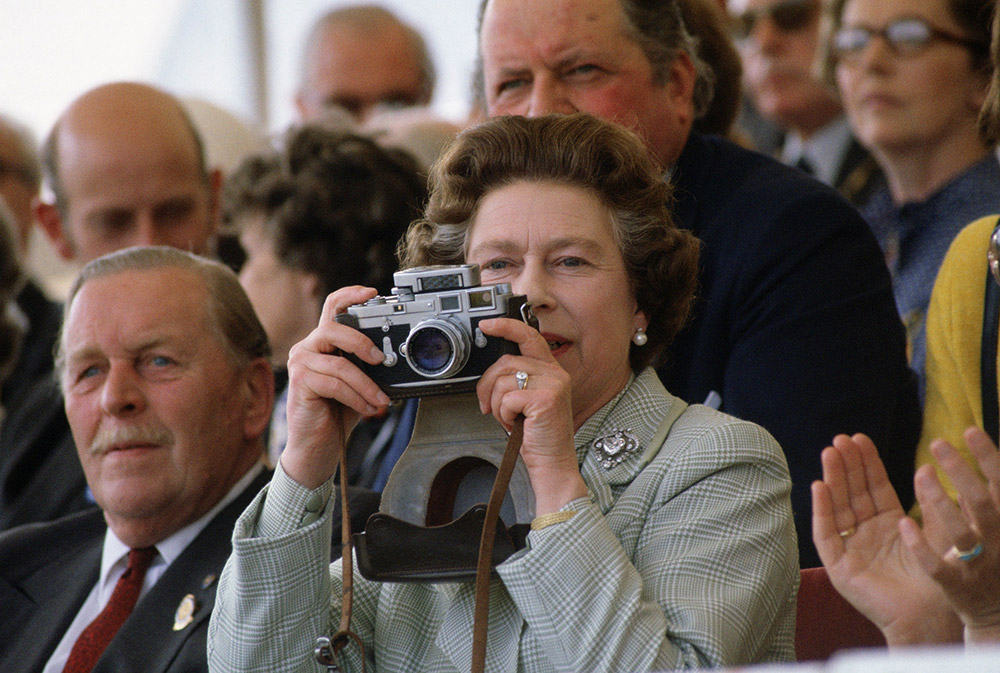 The Queen pictured with her Leica photographing Prince Philip, who was competing in an event at the Royal Windsor Horse Show, 1982. © Tim Graham/Getty Images.