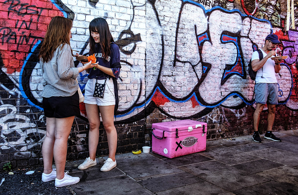 street scene of girls talking in front of graffiti wall
