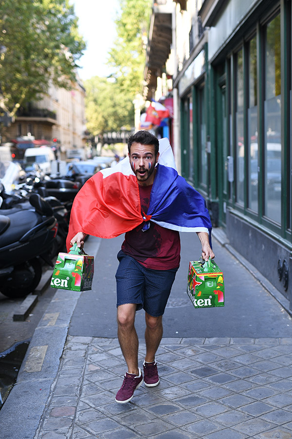 france football fan running in street with flag cape and holding beer