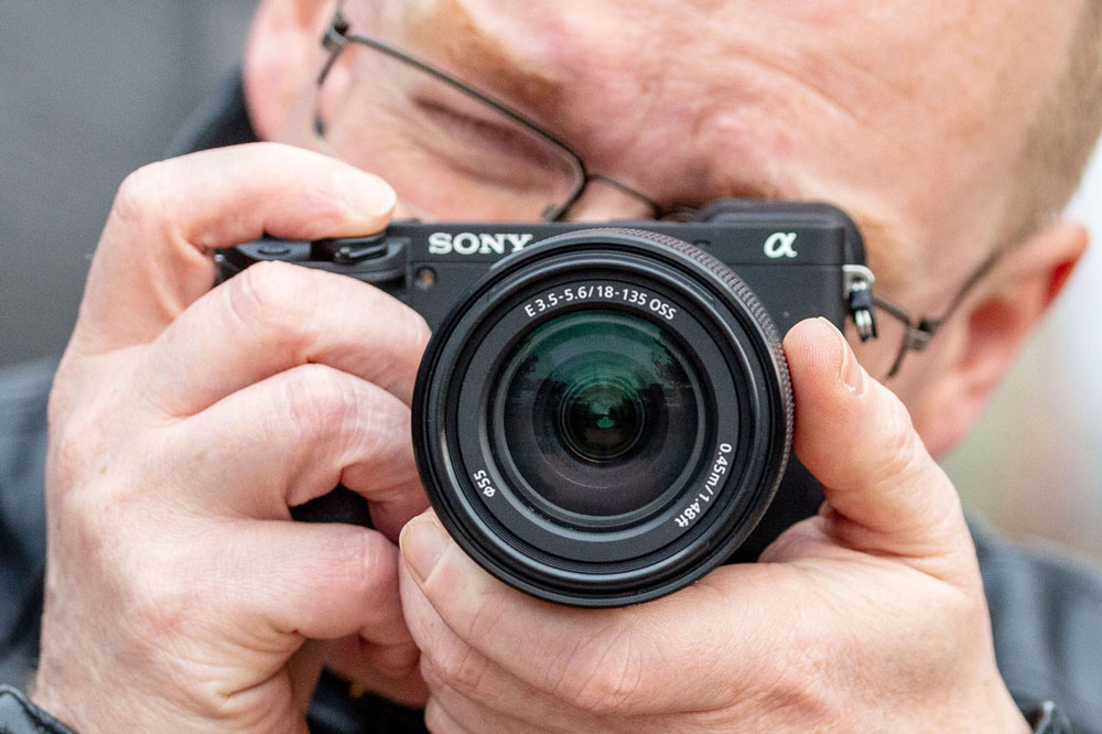 best cameras for portraits Sony Alpha A6400 in hand, with 18-135mm lens, Andy Westlake