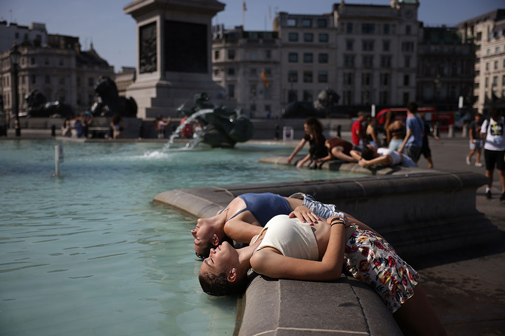 Two women dip their heads into the fountain to cool off in Trafalgar Square on July 19, 2022 in London, United Kingdom by Dan Kitwood/Getty Images