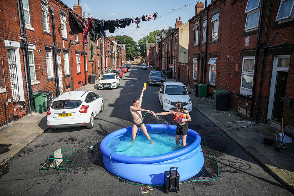 Residents take a dip in a paddling pool to cool off outside their home on July 19, 2022 in Leeds, United Kingdom by Christopher Furlong/Getty Images
