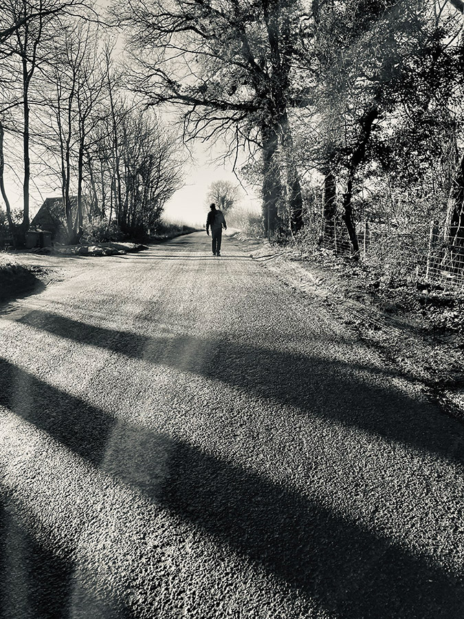 person walking in middle of the road black and white smartphone photography
