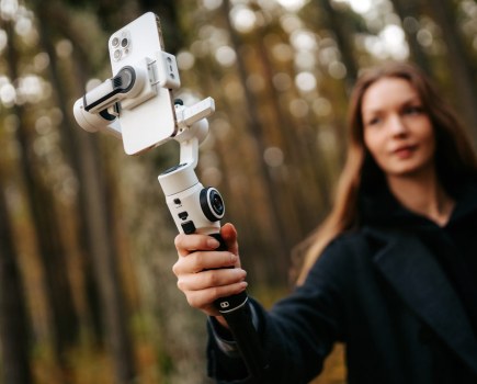 best camera phone tripods and mounts Young woman holding the Zhiyun Smooth 5S Gimbal / Selfie stick up to take a photo with her phone