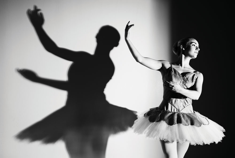 ballerina in pose against white background with dark shadow cast