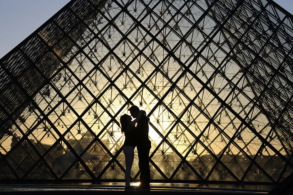 couple stood in front of Louvre pyramid at sunset best cities for street