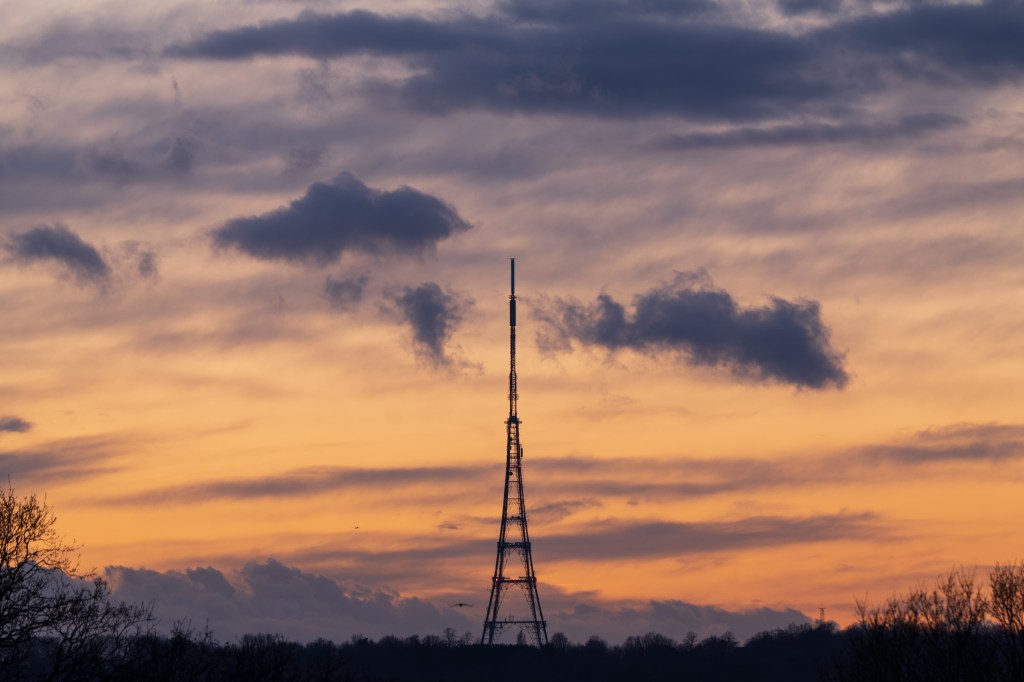 Panasonic Lumix S5II Sync IS 2 telephoto sample image, Orange and purple sunset with streaks of clouds, in the middle the silhouette of a radio tower.
