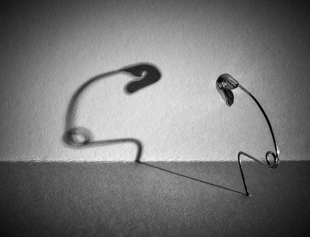 safety pin bent into angle back lighting and facing its shadow black and white apoy winners
