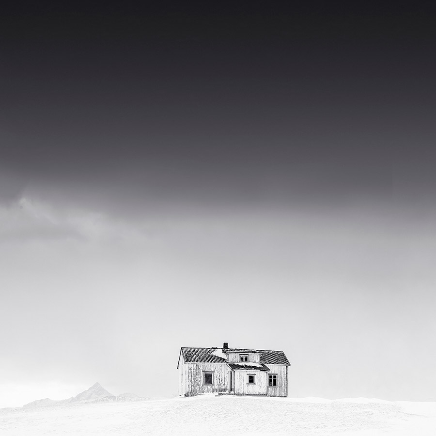 snowy landscape scene with single house on a hill