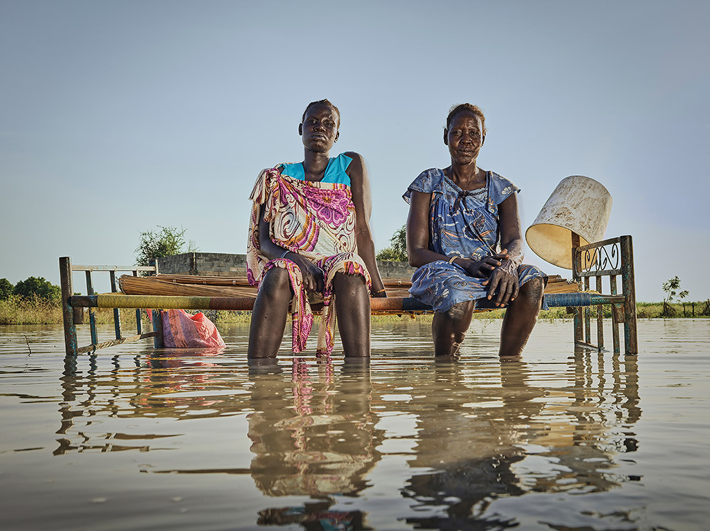 Mother and daughter Nyagout Lok, 46, and Nyakoang Majok, 28, set up a bed in the water so the mother can sleep outside. Image credit: Peter Caton
