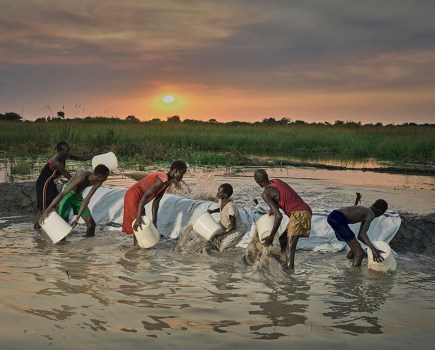 An entire family works into the night trying to scoop out flood water that gushed into their land south sudan floods