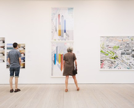 people in a gallery space looking at large photos of buildings in exhibition