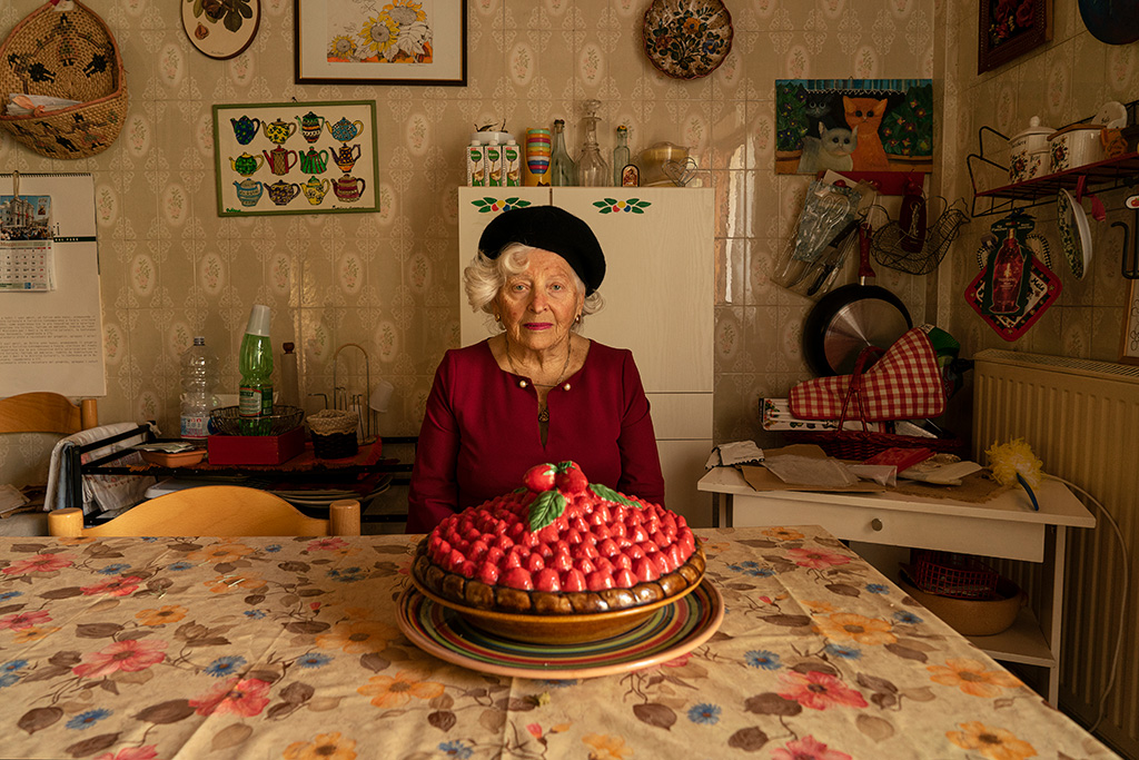 adua sat in her kitchen with a large cake topped with strawberries