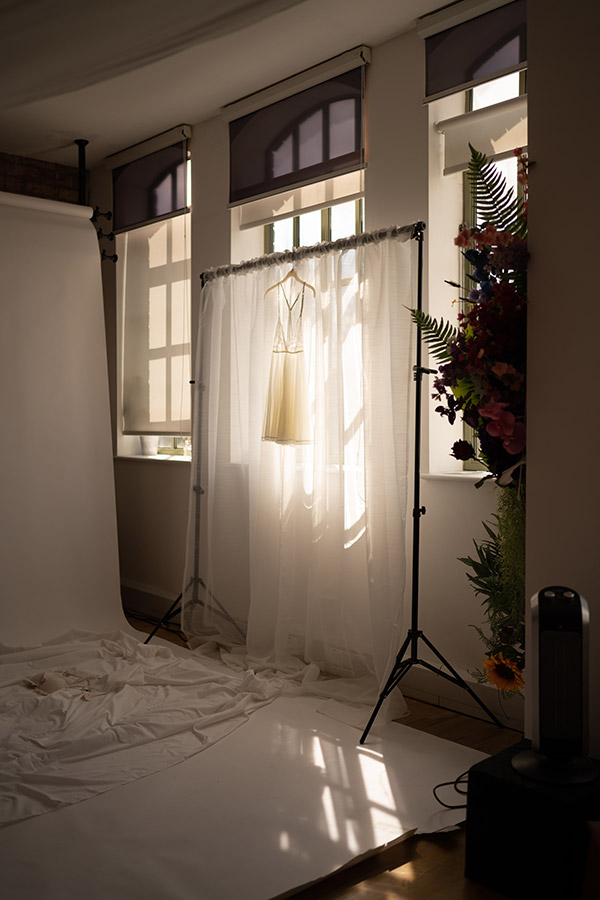 soft natural light coming through a window on a boudoir photography shoot white draping and dress in window