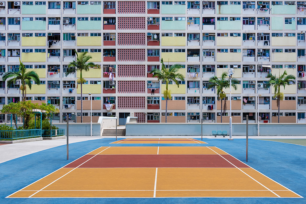 colourful block of flats building behind orange and blue volleyball court