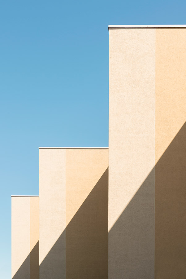 beige buildings against blue sky with shadow coming across building to create geometric shape Unknown building. Lasnamäe, Estonia