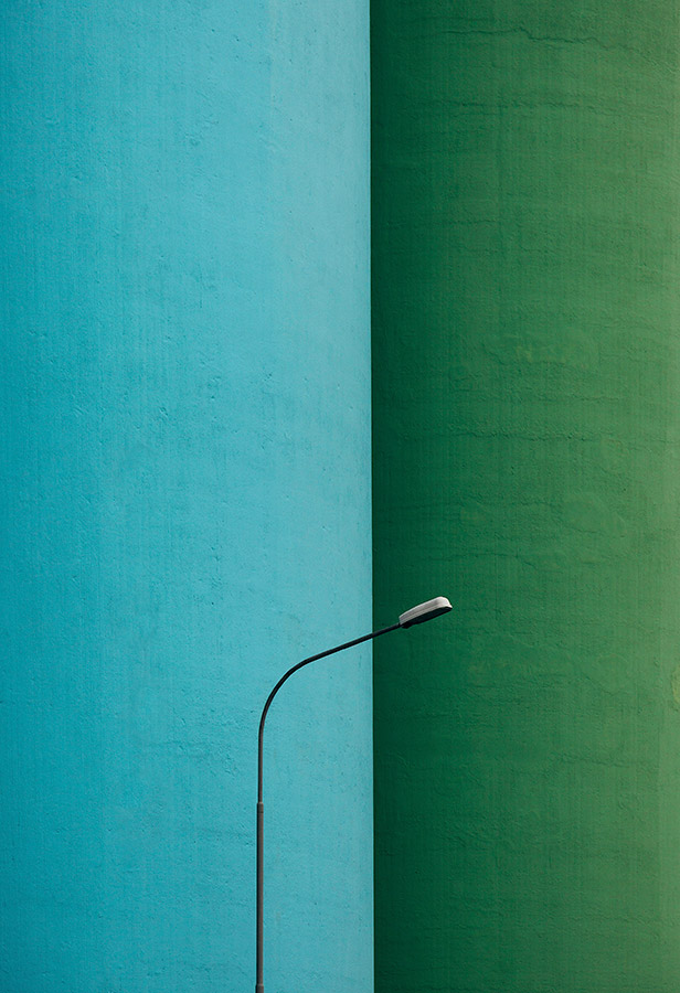 Cement storage silos and lamp post in Akranes, Iceland. against blue and green building abstract