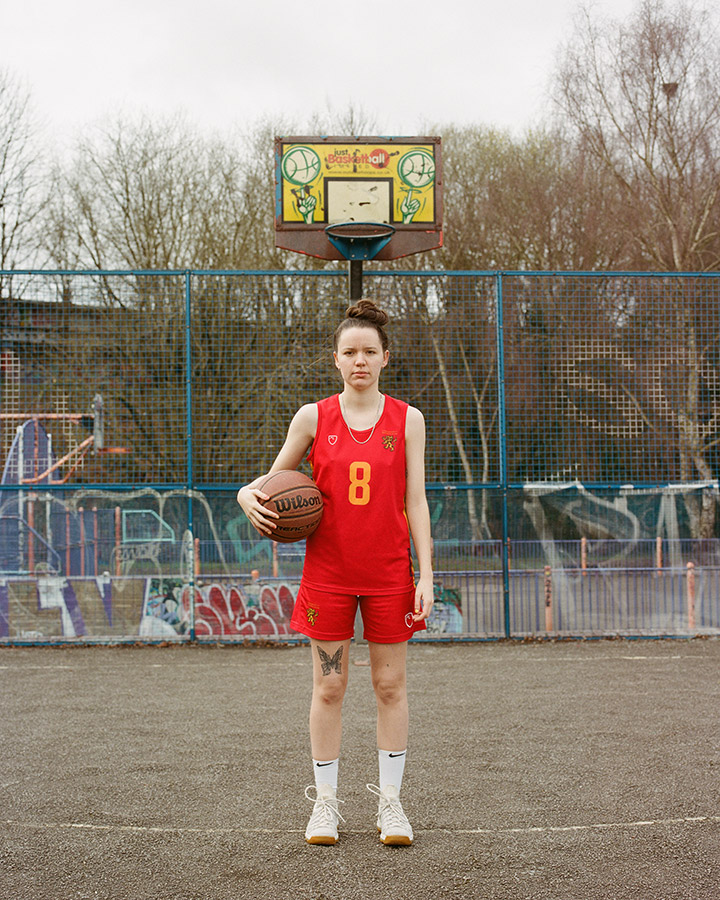 portrait of Lois Hinder basketball player in red outfit stood with basketball