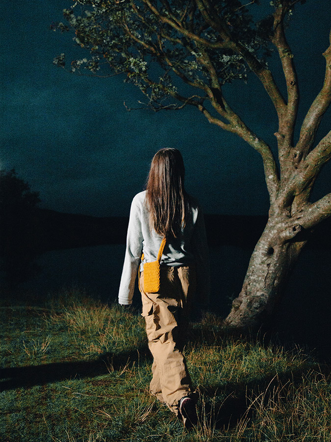 Sorcha Williams posing in dark tree scene with yellow crochet bag photo for sorchacrochet products