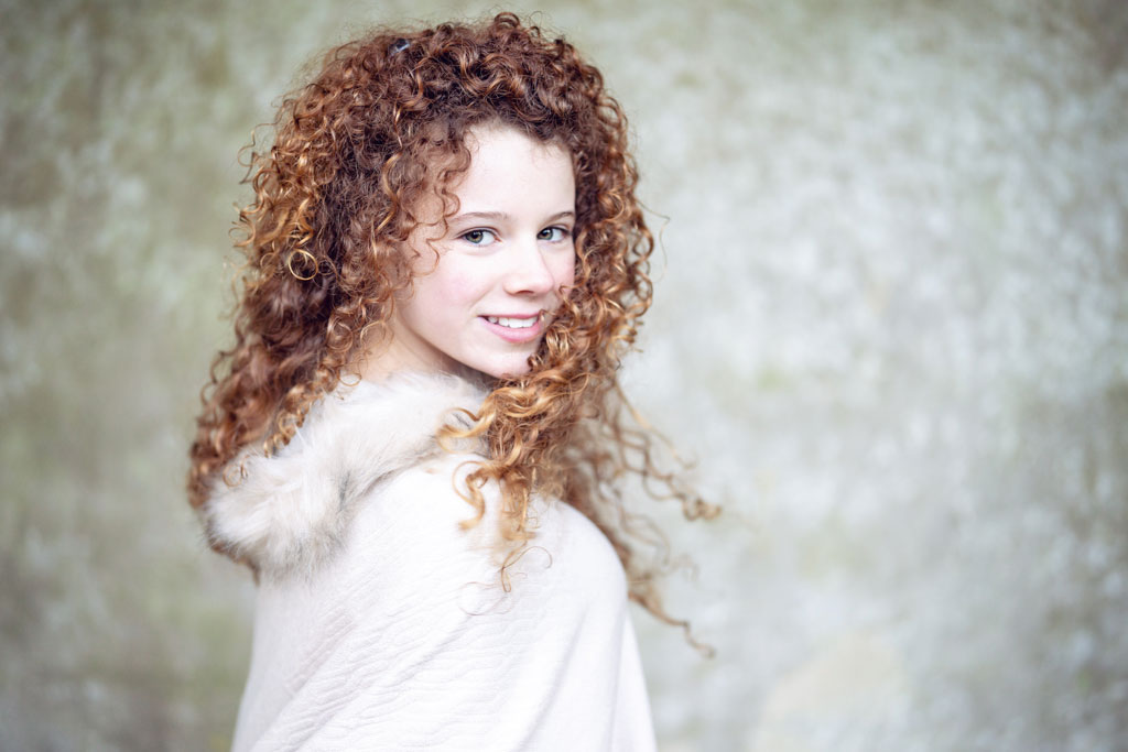 young girl with brown curly hair shot in natural light with some top shade to help angle the light towards the face.