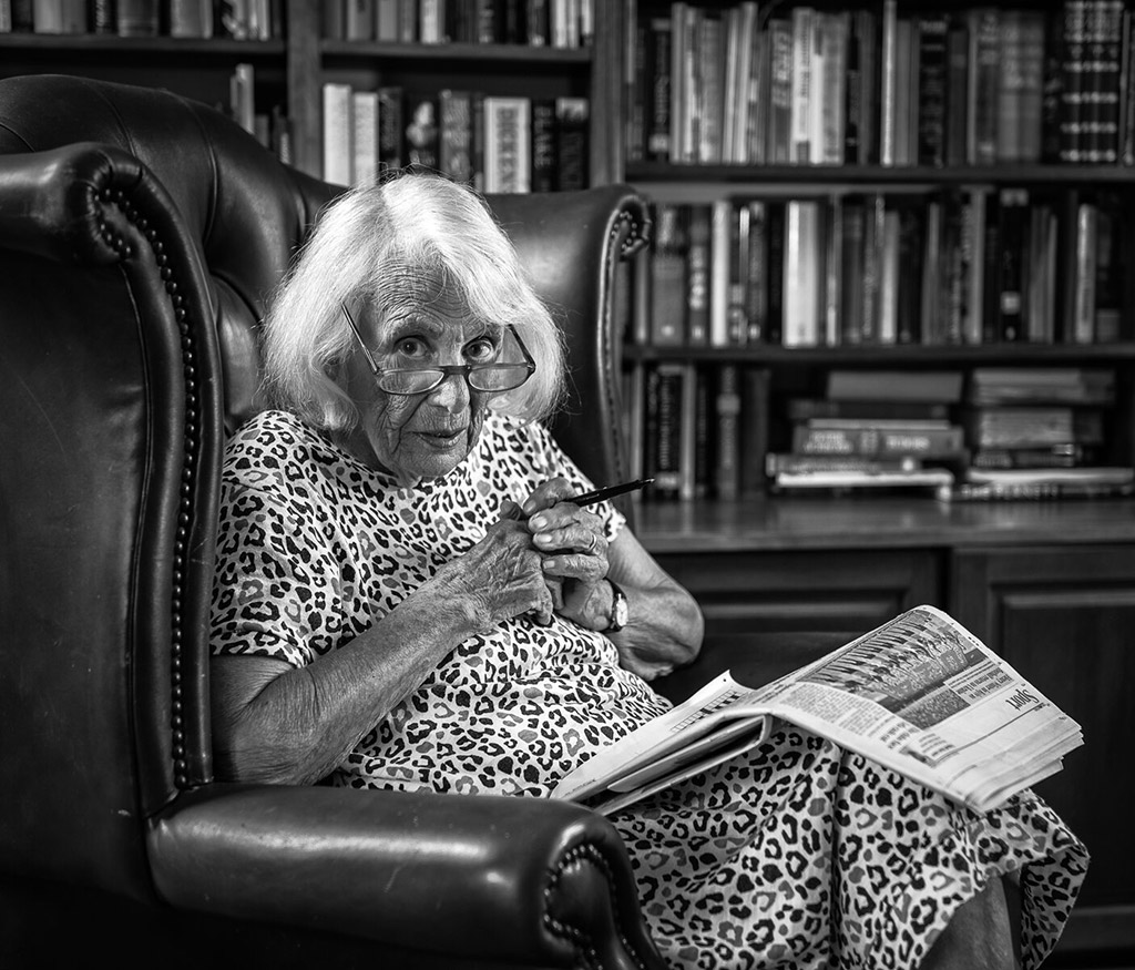 woman gazing over the top of her glasses with paper in lap