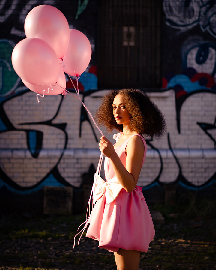 portrait of a girl in pink dress holding pink balloons