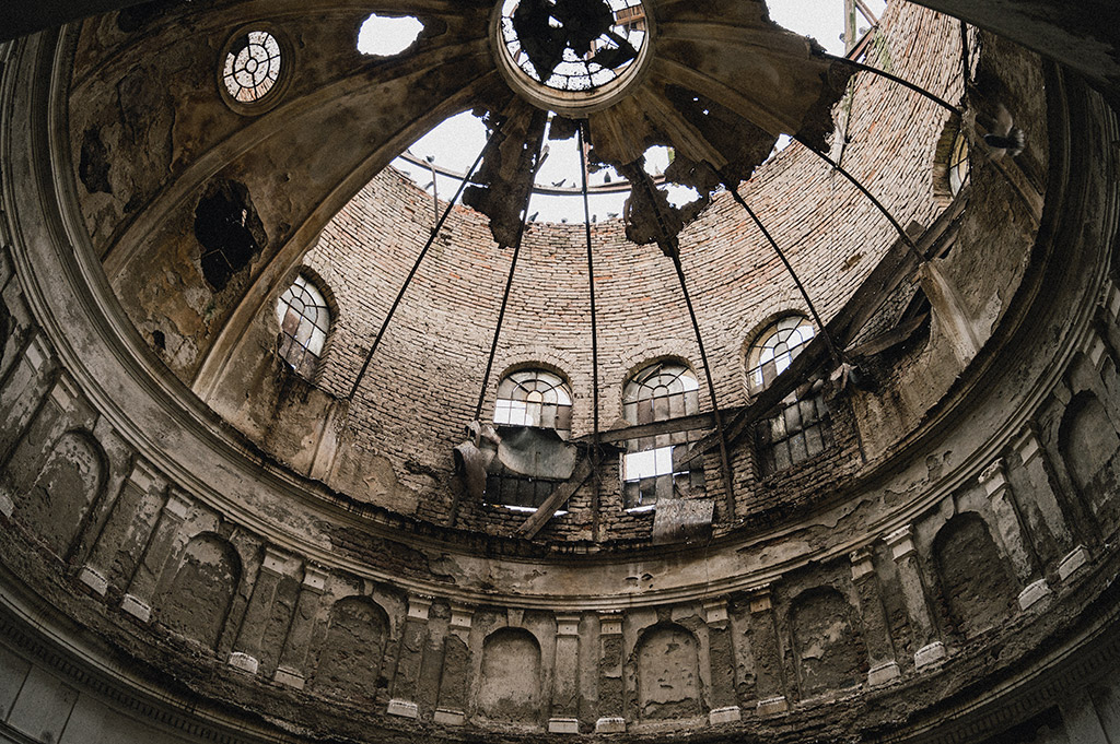 looking up at a ruined building with dome roof collapsing