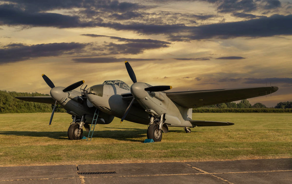 An old grey two propeller military plane on the ground against a dramatic sunset sky, generated with Photoshop sky replacement tool.