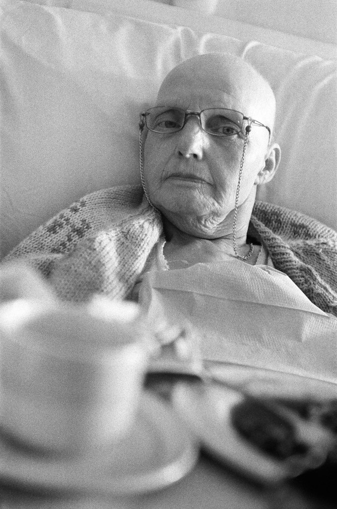 black and white image of an elderly lady laying on bed