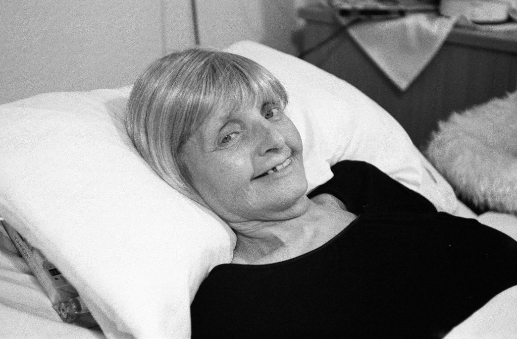 black and white image of an elderly lady laying on bed