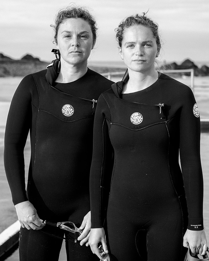 portrait of two people stood wearing wetsuits photography graduate