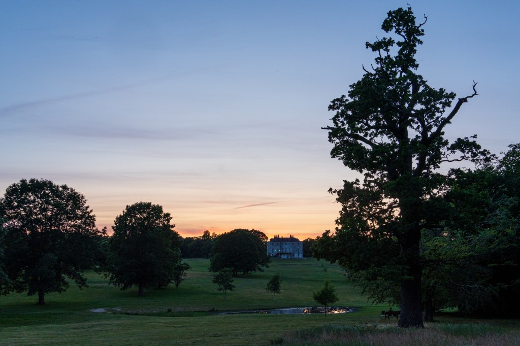Sony Alpha A6700 dynamic range example, country estate on top of a small hill at sunset, in the foreground a park with some trees, sample image
